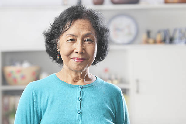 Senior woman posing for the camera Senior Asian woman at home gazing to camera senior women stock pictures, royalty-free photos & images