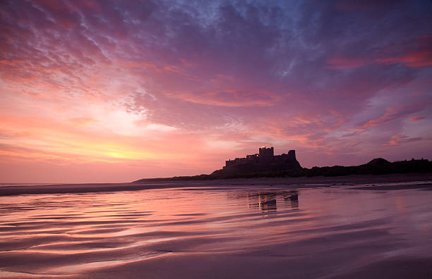 Bamburgh Castle and sands Bamburgh Castle, Northumberland, shot over Bamburgh Beach at sunrise Bamburgh stock pictures, royalty-free photos & images