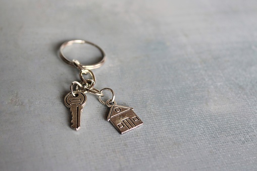 Closeup image of house shaped keychain and key with copy space. Home ownership concept.