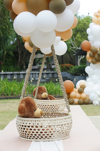 Teddy bear decoration. Creative gender neutral baby shower or birthday decoration in the garden. White cream peach caramel bohemian style outdoor event set up with balloons.