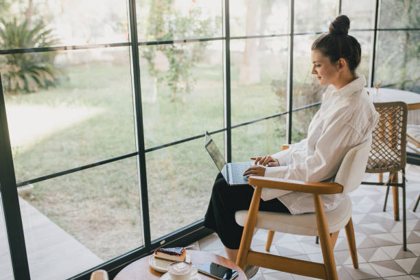 istock Young woman drinking coffee working online using her laptop. 1467851911