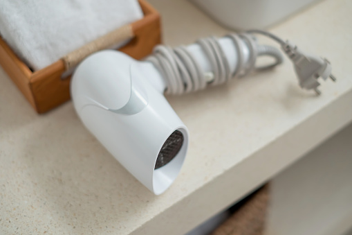 Close-up flatlay shot of white hair dryer and folded clean towel above bathroom counter at luxury villa in Bali