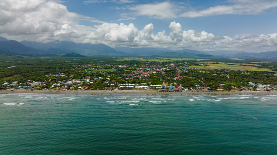 Aerial view of sandy beach and ocean waves. Coastline with hotels and tourists. Sabang Beach, Baler, Aurora, Philippines.