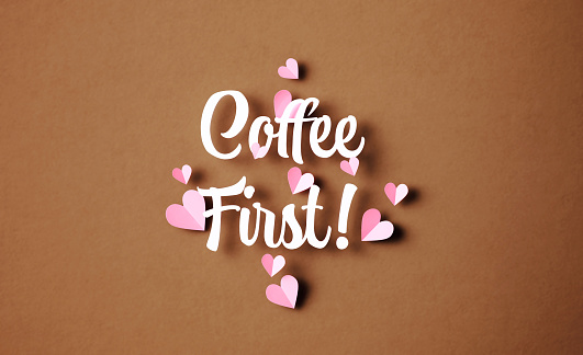 Coffee first phrase surrounded by pink hearts on brown background. Horizontal composition with copy space.