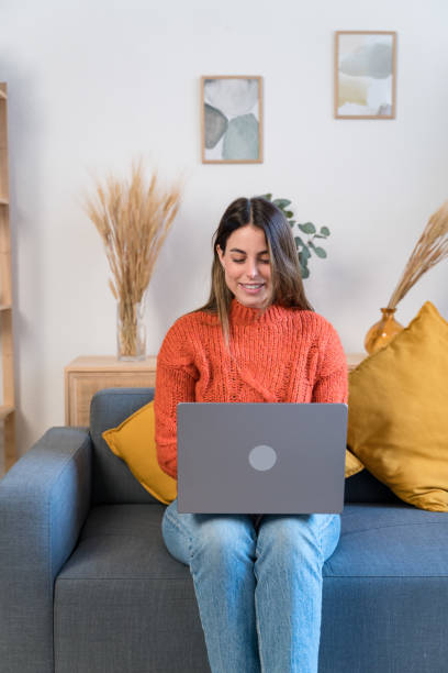 istock Happy woman with laptop on sofa 1467859937