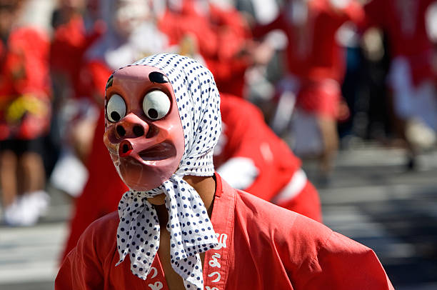A performer wearing a fool mask performing the fool dance, a dance that has steps choreographed to be very funny.