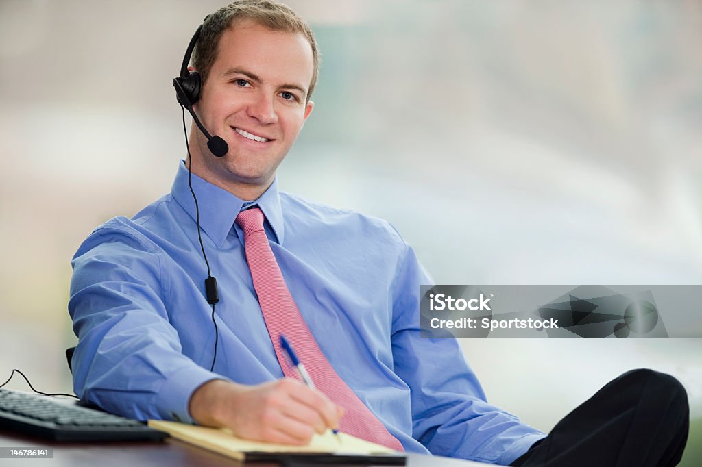 Hombre de negocios joven sentado en su oficina usando auriculares - Foto de stock de Adulto libre de derechos