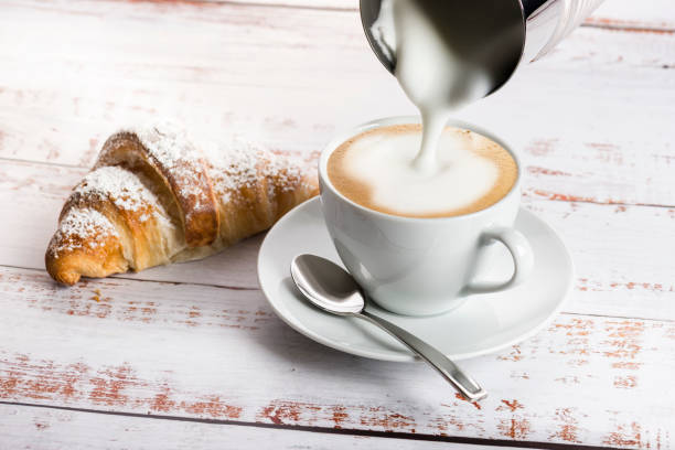 Cappuccino on wooden table Making cappuccino with milk frother on wooden table with croissant. cappuccino coffee froth milk stock pictures, royalty-free photos & images