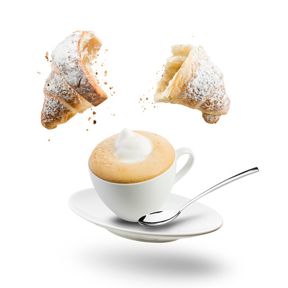 Breakfast with cup of cappuccino and croissant. Floating on white background.
