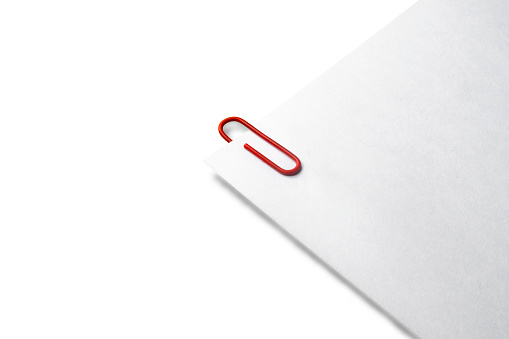 White sheets held together by a red paper clip with shading and lot of copy space