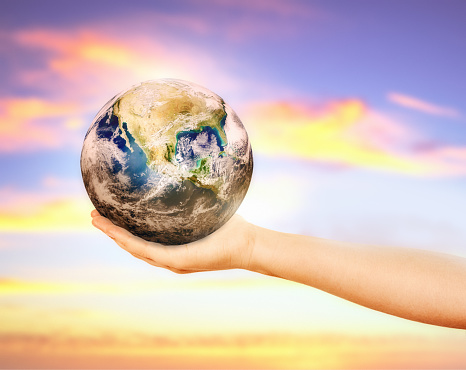 Woman holds the Earth in the palm of her hand outdoors, with a pastel multi-colored sky in the background. Public domain satellite image from https://www.nasa.gov/multimedia/imagegallery/image_feature_2159.html