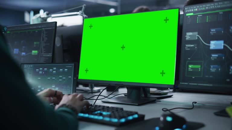 Close Up of a Software Developer Working on a Desktop Computer with Green Screen Mock Up Display. Specialist Typing on Keyboard, Coding and Implementing a New Technical Feature. Static Footage