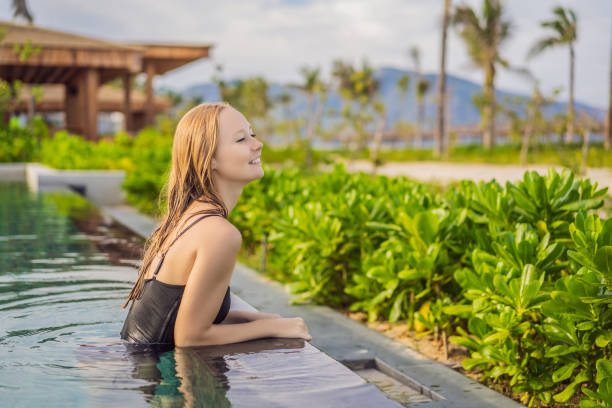 istock Woman relaxing in infinity swimming pool looking at view 1467865539
