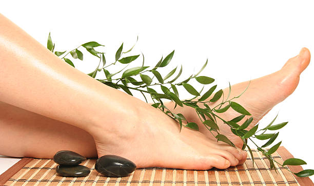 Portrait of feet with massage stones and foliage on bamboo stock photo