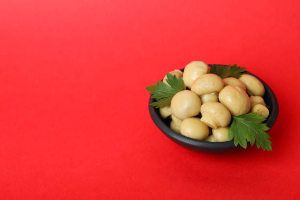 Bowl of marinated mushrooms on red background