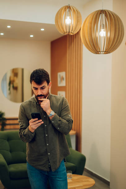 istock Caucasian man with beard using smartphone at home 1467869286