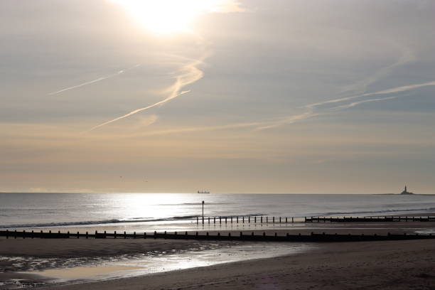 istock Dawn over a calm sea and a long sandy beach with a distant lighthouse 1467869996