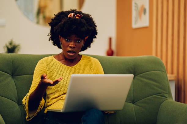 istock Stressed african american woman using laptop while sitting on a couch at home 1467870573