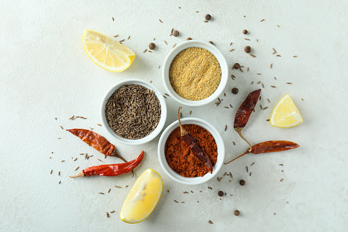 Aromatic spices in white bowls on textured background