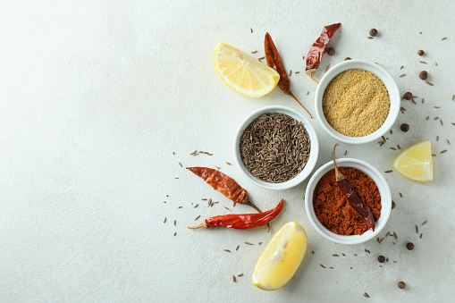 Aromatic spices in white bowls on textured background