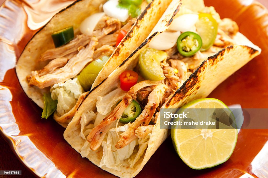 Plate of chicken tacos with half a lime shredded chicken tight accompany cabbage and a chunky salsa verde Chicken Taco Stock Photo