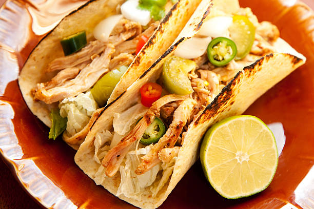 Plate of chicken tacos with half a lime shredded chicken tight accompany cabbage and a chunky salsa verde tomatillo photos stock pictures, royalty-free photos & images