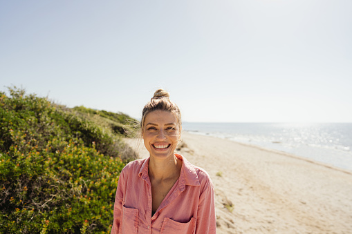 Photo of a young smiling woman spending summer afternoon on the local beach