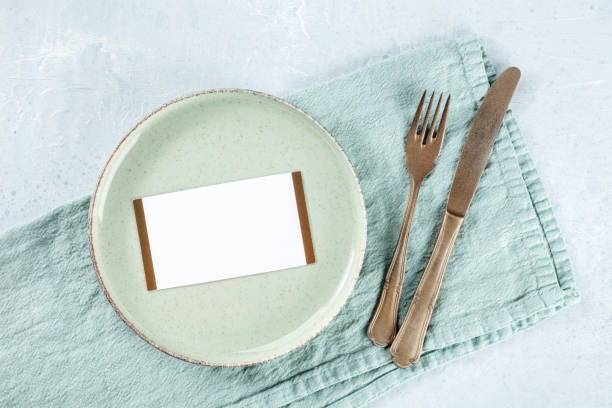 Dinner invitation. A card on a green plate, with silverware stock photo