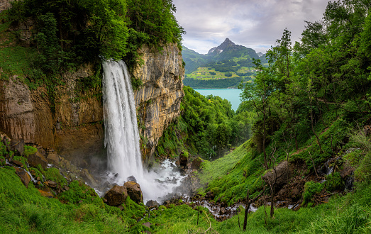 A mighty waterfall flowing from a mountain surrounded by green grass