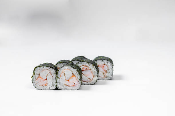 Maki shrimp sushi. Shrimp fillet stuffing wrapped in rice and nori seaweed. Sushi stands on a white background.