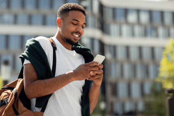 istock Happy black man enjoying free time outdoors, texting on smartphone or surfing in internet while walking in urban city 1467886270