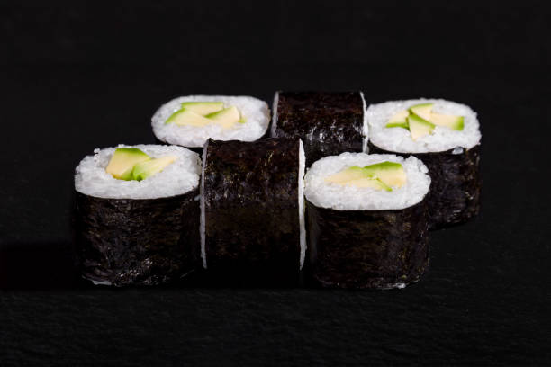 istock Rolls with nori, rice and avocado on black stone background 1467886608