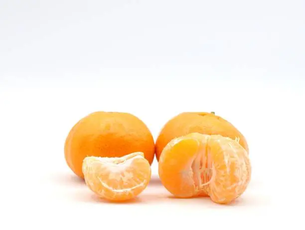 A closeup of peeled mandarins on a white surface, isolated on white background