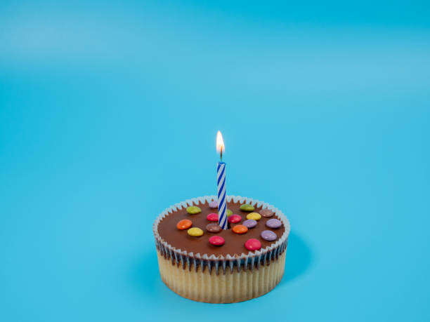 istock Muffin with a candle on a blue background. Holiday muffin. 1467887533