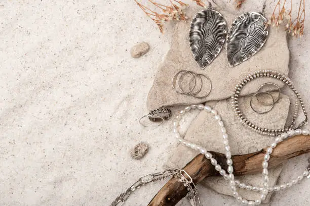 Photo of Beautiful Silver and Pearl Jewelry on white sand.