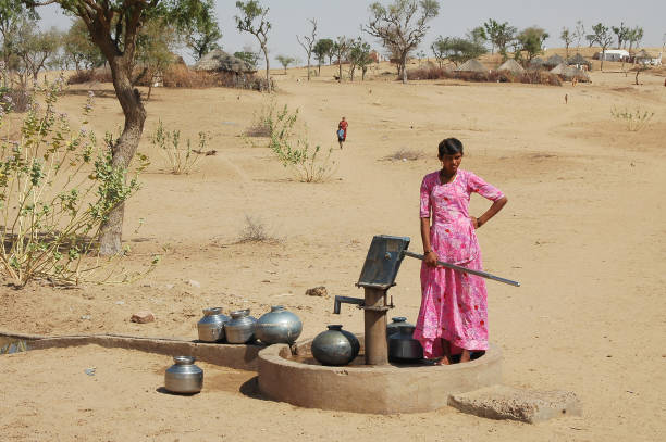 Rajasthan, India - March 03, 2006: Young woman drawing water from a well in a rural area of the region