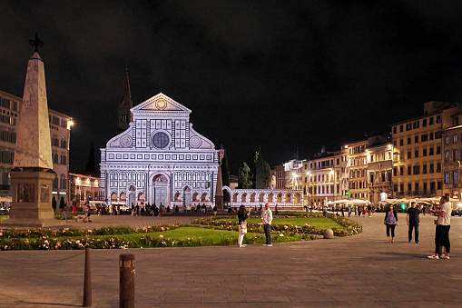 Florence, Italy - September 10, 2022: Pedestrians in front of Santa Maria Novella church at night.