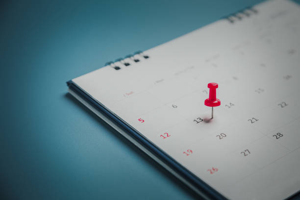 gestickte rote stifte auf einem kalender event planer kalender, uhr zum einstellen des zeitplans organisieren zeitplan, planung für geschäftstreffen oder reiseplanungskonzept. - calendar calendar date reminder thumbtack stock-fotos und bilder