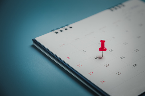 Embroidered red pins on a calendar event Planner calendar,clock to set timetable organize schedule,planning for business meeting or travel planning concept.