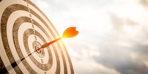ダークブルーの空の背景にダーツボードセンターのターゲットにショット赤ダーツの矢印をクローズアップ。ビジネス目標または目標の成功と勝者の概念。 - target ストックフォトと画像