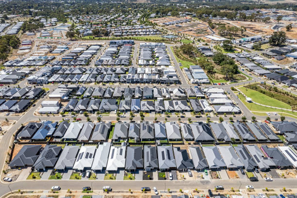 istock Aerial view new dense rural housing development, mostly grey roofing, some green landscaping, young trees, construction site 1467895800