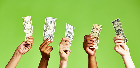 Group of people with their hands raised, holding various American dollar banknotes, on a green background.