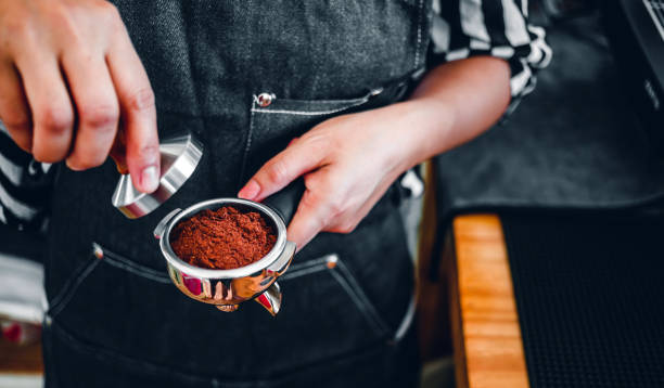 barista holding portafilter and coffee tamper making an espresso coffee in cafe - tamper imagens e fotografias de stock