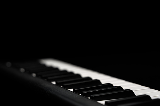 Electronic keyboard close up, mostly out of focus against the black background. Copy space.