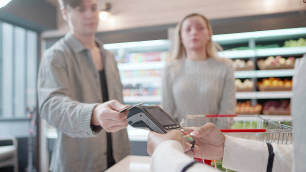 istock Customer paying using credit card and NFC technology in supermarket. Male is checkout puts a credit card to the terminal. Contactless payment method for goods and products at the cashier. Enjoying lifestyle in spending digitally, with comfortable life. 1467899049