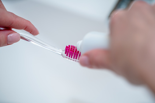 Close-up of toothbrush and a tube of toothpaste in a woman's hands