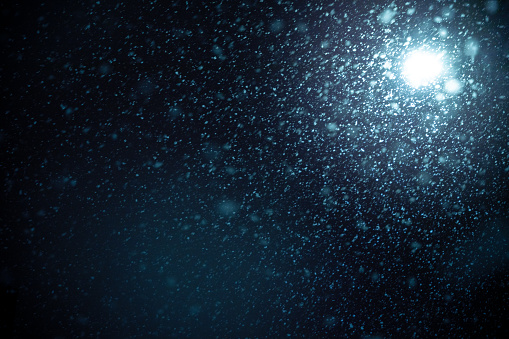 Bright lens flare and snowfall blurred in motion isolated on black background.