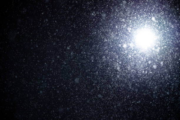 istock Bright lens flare and snowfall blurred in motion isolated on black background. 1467900607