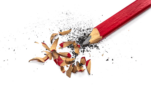 Red wooden carpenter's pencil sharpened with knife. Close up with shavings and bits of graphite.