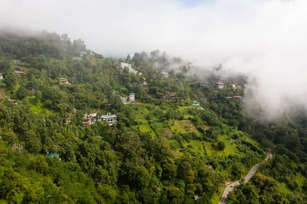 Houses on the slopes of mountains covered with fog and clouds. Ella, Sri Lanka.